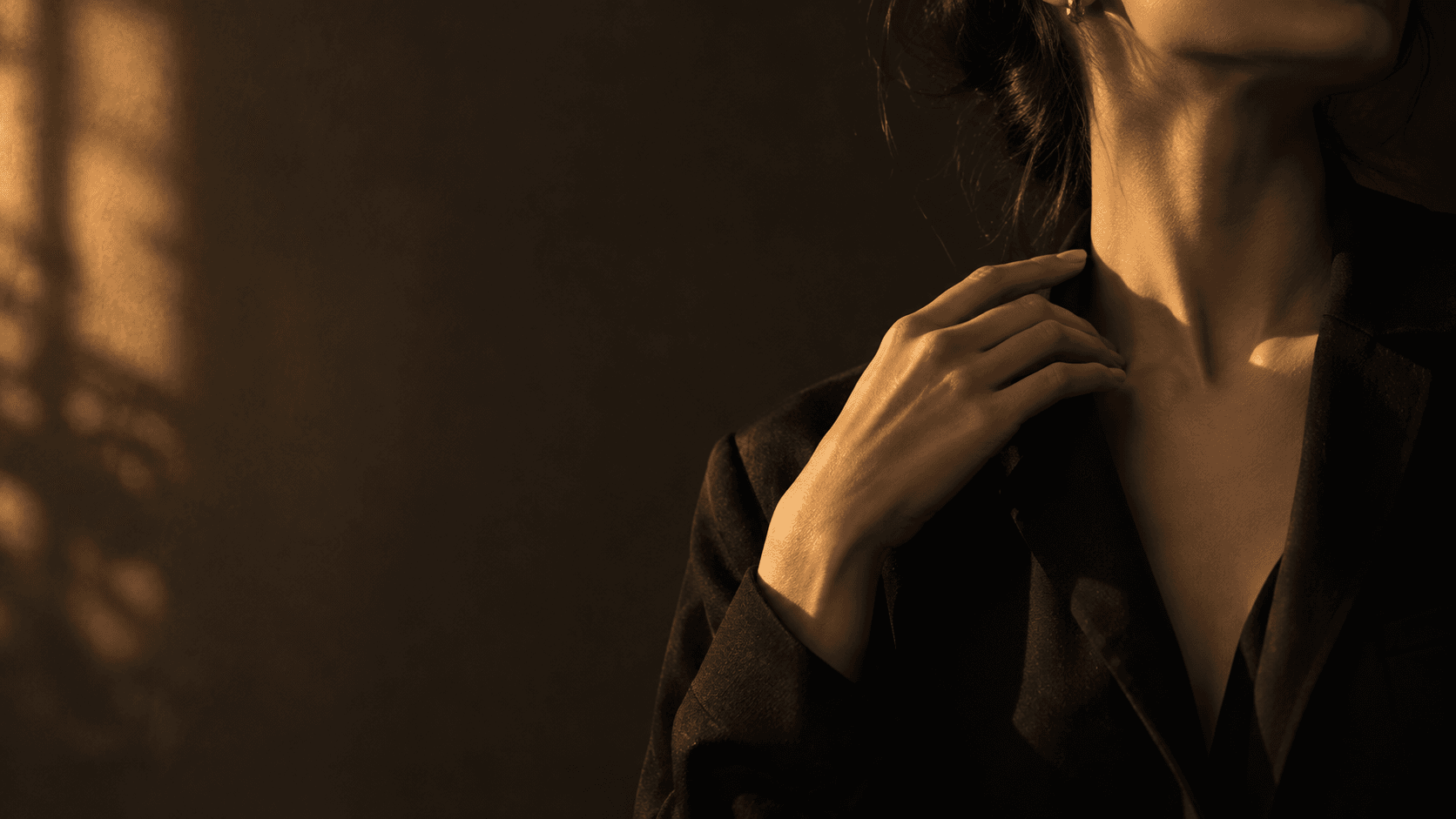 A hand rests near the collarbone in warm light